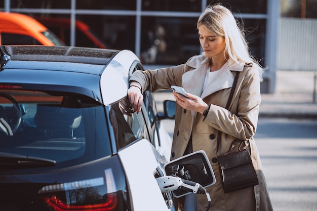 Woman charging electro car at the electric gas station