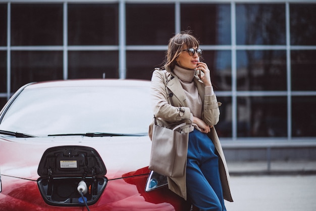 Donna che carica l'auto elettrica alla stazione di gas elettrica