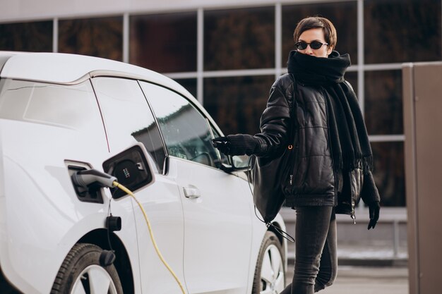 Woman charging electro car at the street