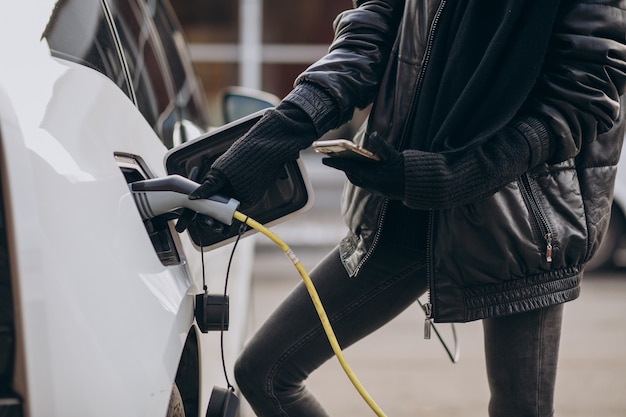 Woman charging electro car at the street