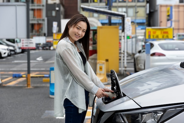 Женщина заряжает свой электромобиль на станции