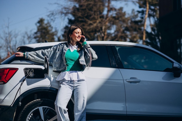 Free photo woman charging her electric car with charging pistol