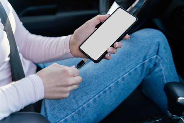 Женщина заряжает свой телефон в машине