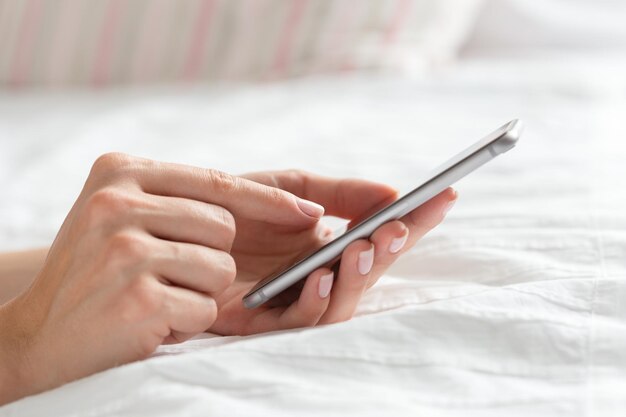 Woman checking the cell phone on the bed