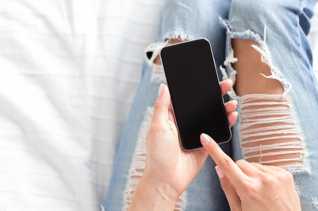 Woman checking the cell phone on the bed