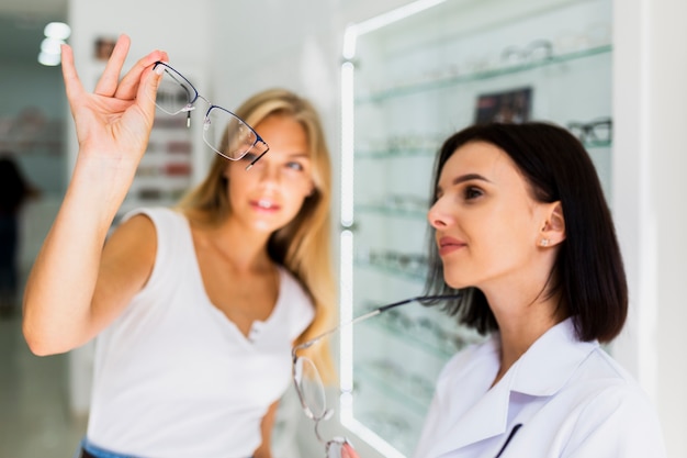 Woman checking eyeglasses frame in shop