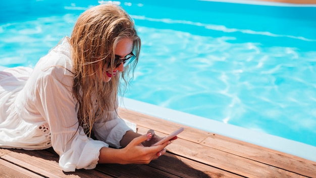 Free photo woman checking her phone at the pool