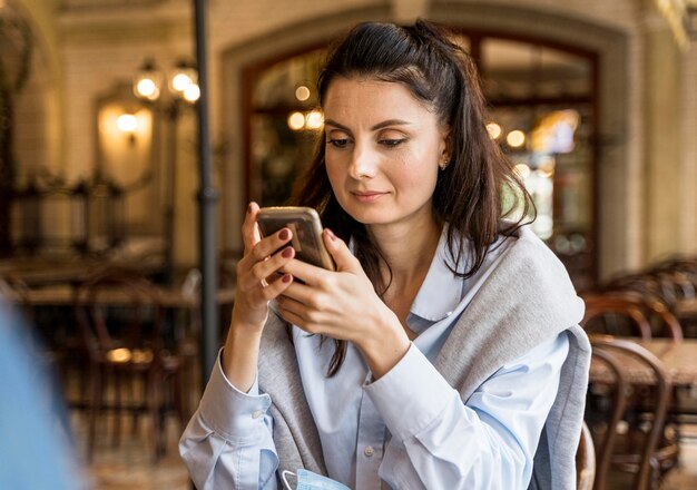 Женщина проверяет свой телефон в ресторане