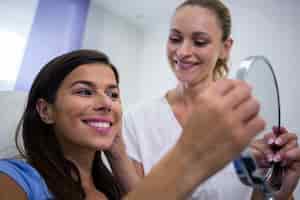 Free photo woman checking her skin in the mirror after receiving cosmetic treatment