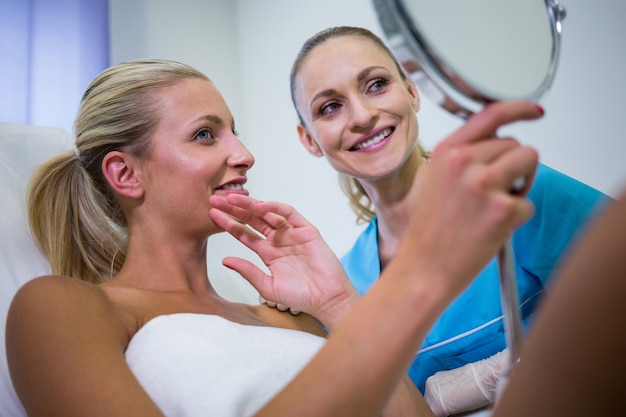 미용 치료를받은 후 거울에 그녀의 피부를 확인하는 여자
