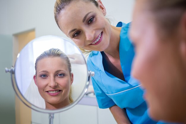 Woman checking her skin in the mirror after receiving cosmetic treatment