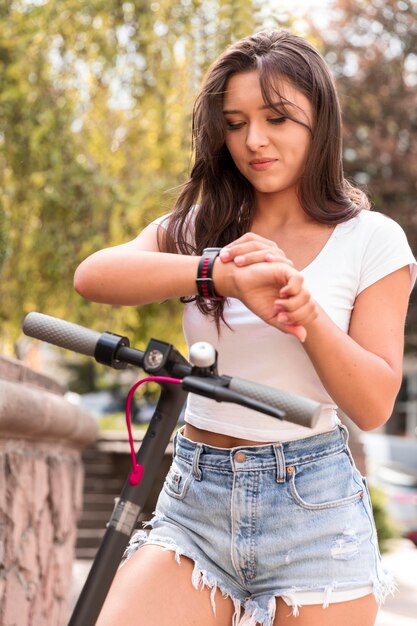 Woman checking her smartwatch while on electric scooter