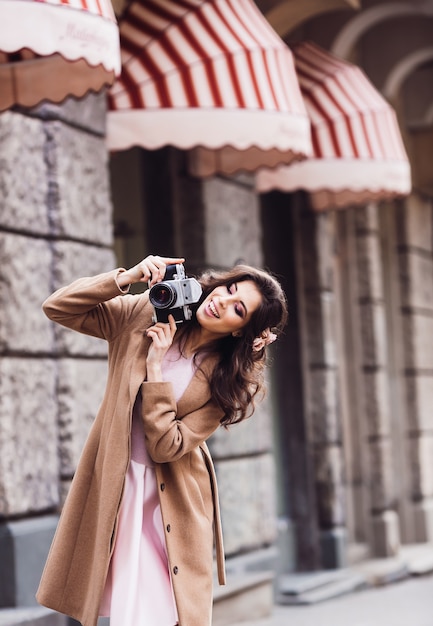 Free photo woman checks her retro camera standing on the street