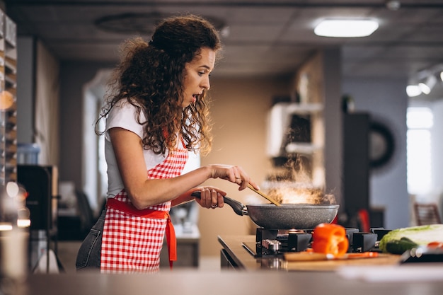 Woman chef cooking vegetables in pan