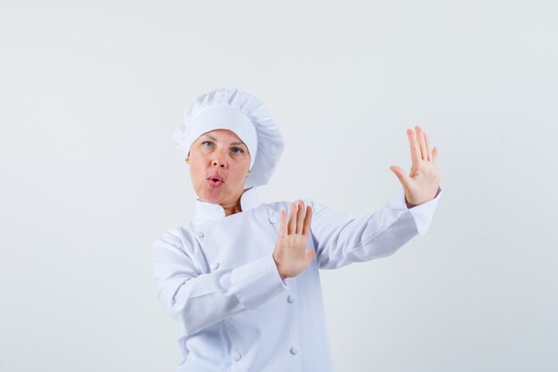 woman chef defending herself in white uniform and looking anxious