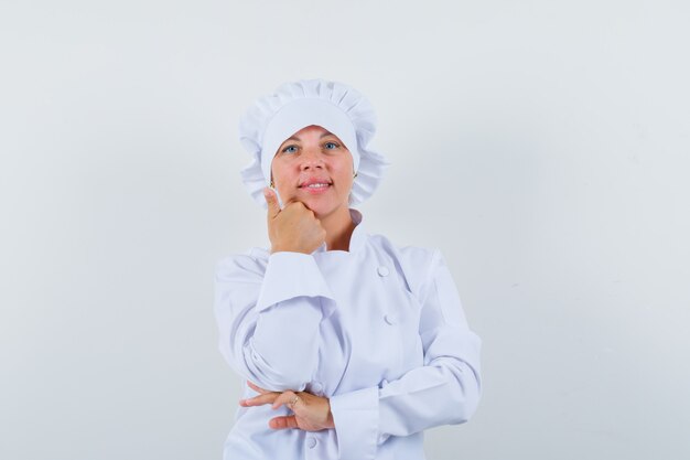 Chef donna che tiene la mano sul mento in uniforme bianca e che sembra ragionevole.