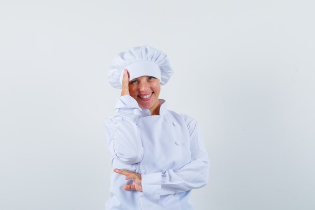 흰색 유니폼을 입고 머리에 손을 잡고 부끄러워 보이는 여자 요리사