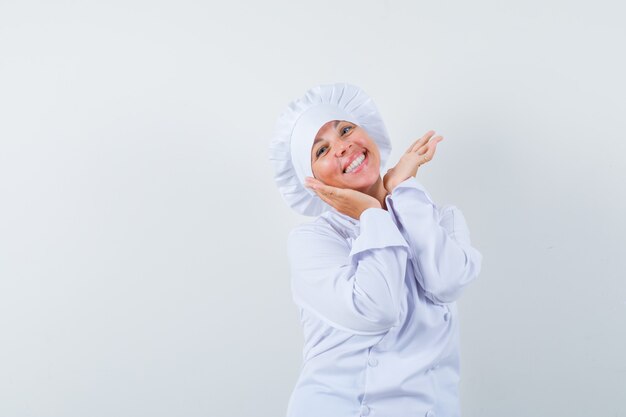 woman chef holding hands under chin in white uniform and looking cute