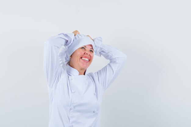 woman chef holding hands on head in white uniform and looking blissful.