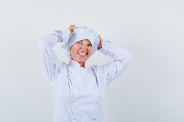 женщина-шеф-повар, взявшись за руки в белой форме и выглядя счастливым.