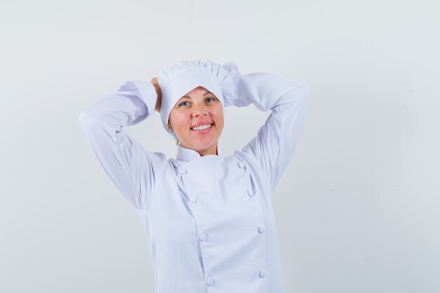 woman chef holding hands on head in white uniform and looking peaceful.