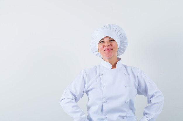 женщина-повар держит руки за талию в белой форме и выглядит уверенно