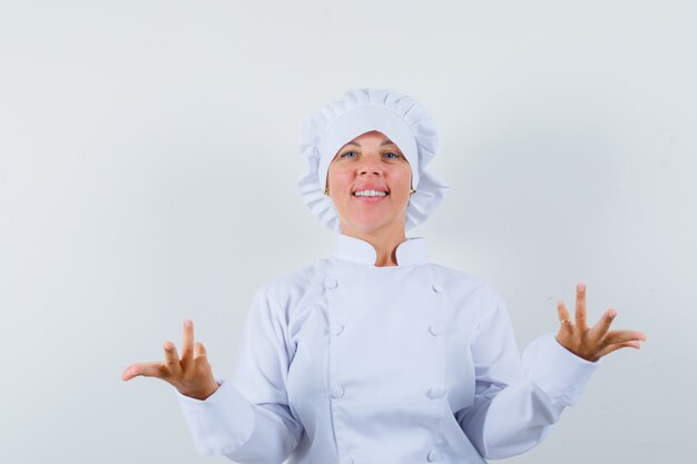женщина-шеф-повар держит руки в вопросительном жесте в белой форме и выглядит уверенно