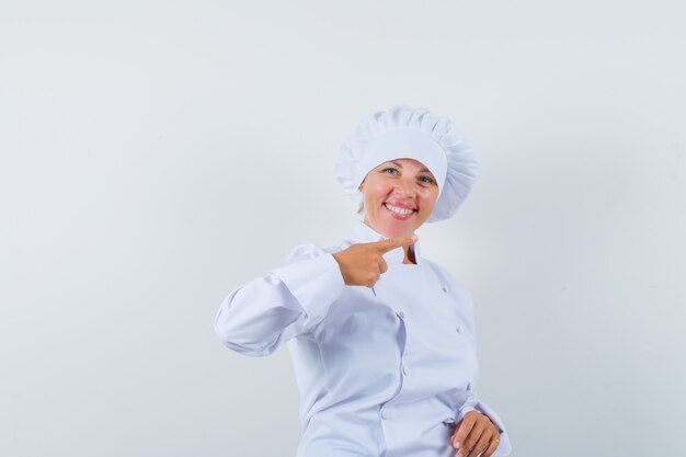женщина-повар, указывая в сторону в белой форме и выглядя счастливой