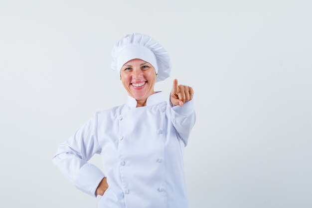 woman chef pointing forward in white uniform and looking merry