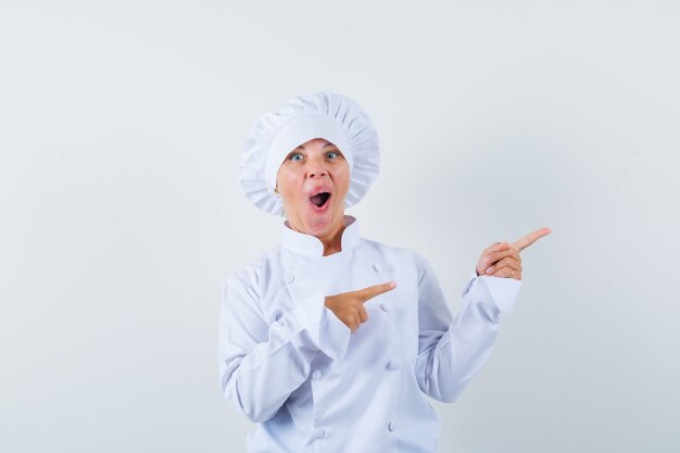 흰색 제복을 입은 오른쪽 상단 모서리를 가리키고 놀란 여자 요리사
