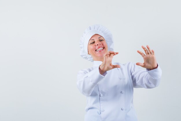 женщина-повар позирует, как фотографировать кого-то в белой форме и выглядит позитивно.