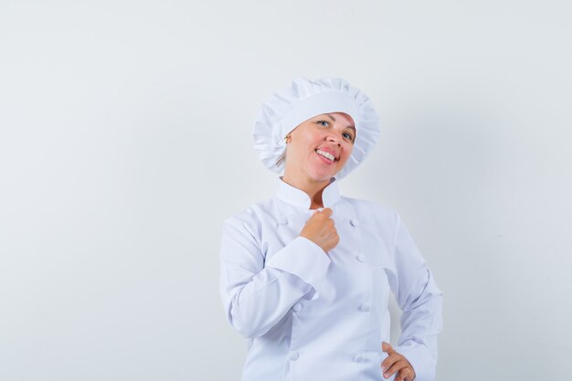 woman chef posing while standing in white uniform and looking cheerful.