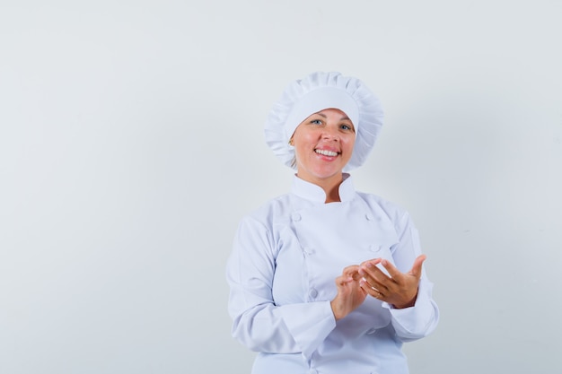 woman chef pretending to use mobile phone in white uniform and looking happy