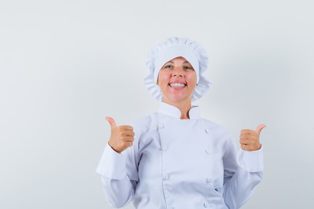 woman chef showing double thumbs up in white uniform and looking confident.