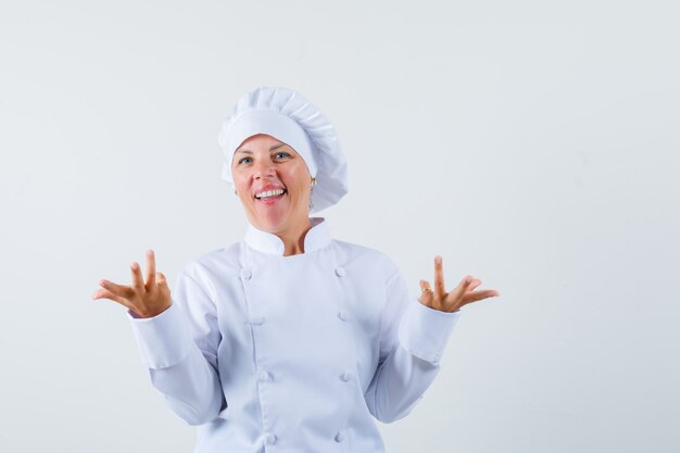 woman chef showing helpless gesture in white uniform and looking puzzled