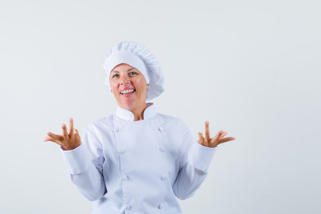 흰색 제복을 입은 무력한 제스처를 보여주는 여자 요리사와 의아해 보이는