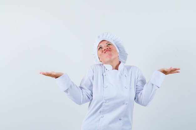 woman chef showing helpless gesture in white uniform.