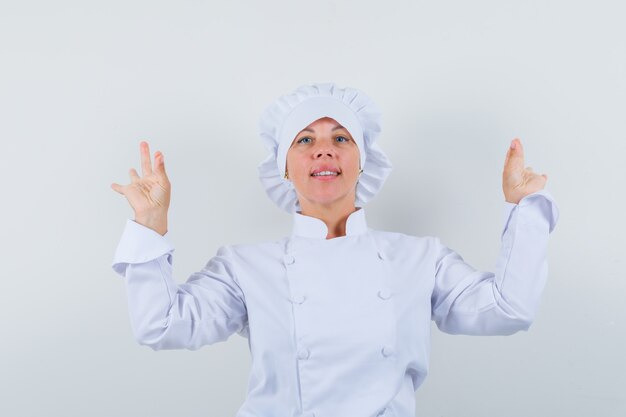 женщина-повар показывает жест медитации в белой форме и выглядит уверенно.