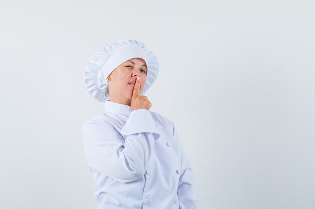 woman chef showing silence gesture in white uniform and looking sensible