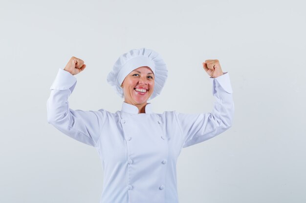 woman chef showing winner gesture in white uniform and looking happy