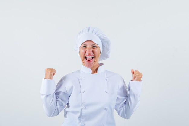 woman chef showing winner gesture in white uniform and looking happy.