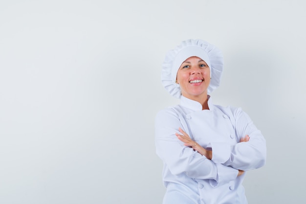 woman chef standing with crossed arms in white uniform and looking confident