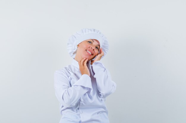 woman chef touching her cheek in white uniform and looking graceful.