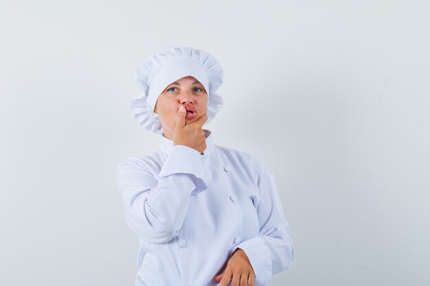 woman chef in white uniform holding hand on chin and looking hesitant