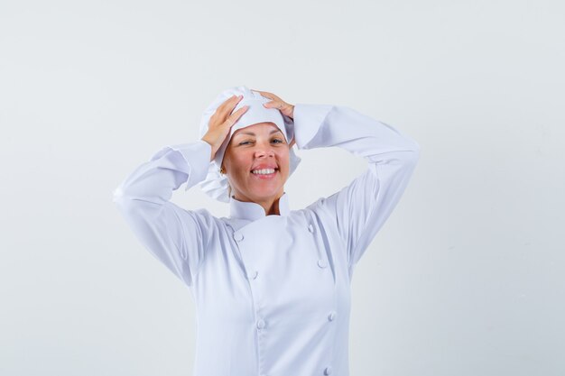 woman chef in white uniform holding hands on head and looking optimistic