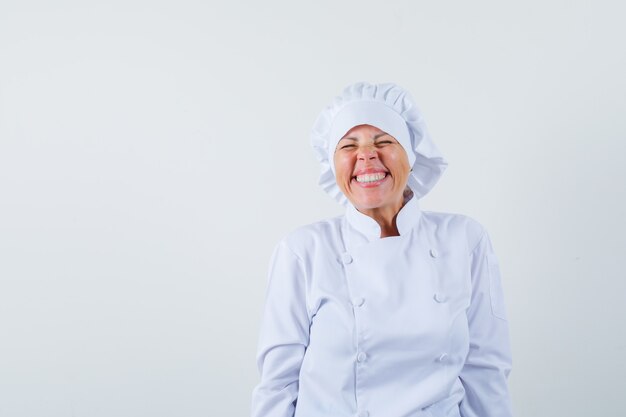 женщина-повар в белой форме смеется с закрытыми глазами