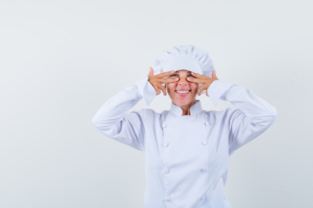 woman chef in white uniform looking through fingers and looking joyful