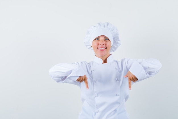 woman chef in white uniform pointing down and looking confident