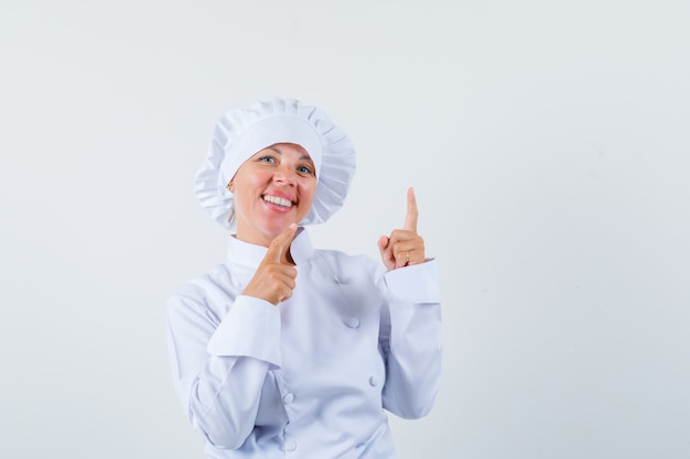 woman chef in white uniform pointing up and looking merry