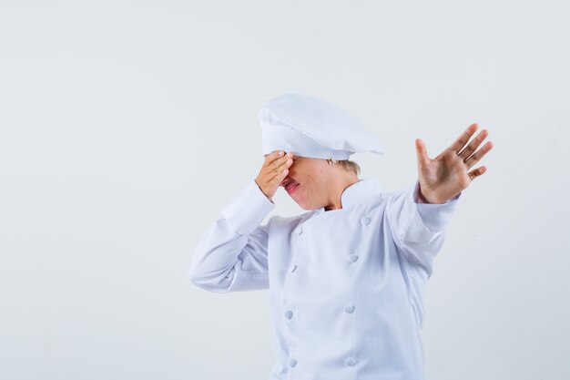 woman chef in white uniform posing like showing phone and looking dissatisfied